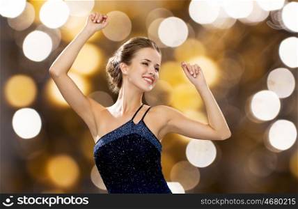 people, party, holidays and glamour concept - smiling woman dancing with raised hands over lights background