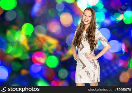 people, party, holidays, hairstyle and fashion concept - happy young woman or teen girl in fancy dress with sequins and long wavy hair over disco lights background