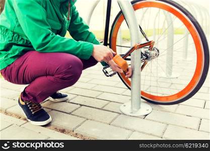 people, people, security, safety and transport - close up of man fastening bicycle lock on street parking