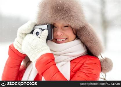 people, photography and leisure concept - happy woman in winter fur hat with film camera photographing outdoors. happy woman with film camera outdoors in winter