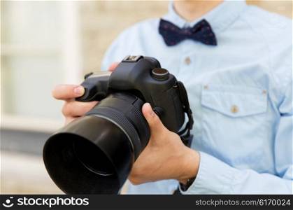 people, photography, technology, leisure and lifestyle - close up of male photographer with digital camera on city street