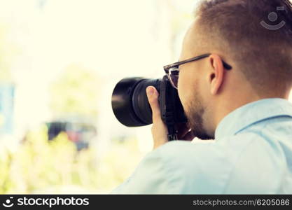 people, photography, technology, leisure and lifestyle - close up of male photographer with digital camera on city street