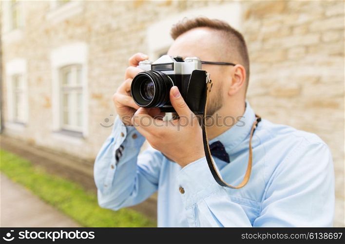 people, photography, technology, leisure and lifestyle - close up of young hipster man with retro vintage film camera on city street