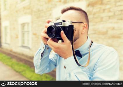 people, photography, technology, leisure and lifestyle - close up of young hipster man with retro vintage film camera on city street