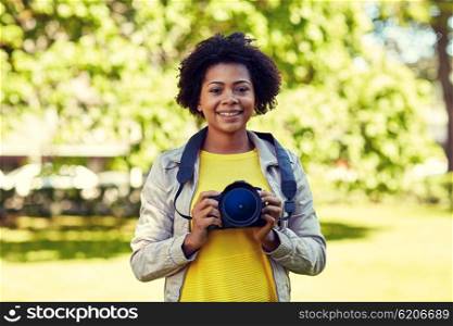 people, photography, technology, leisure and lifestyle - happy young african american female photographer with digital camera in summer park