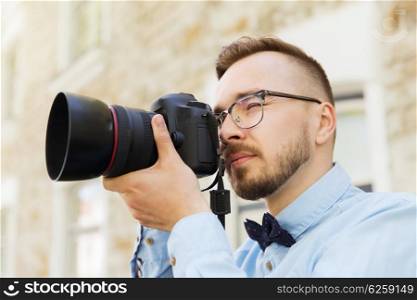 people, photography, technology, leisure and lifestyle - happy young hipster man holding digital camera with wide angle lens taking picture on city street