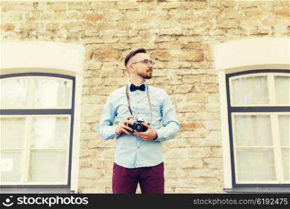 people, photography, technology, leisure and lifestyle - happy young hipster man with retro vintage film camera on city street