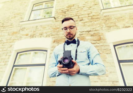 people, photography, technology, leisure and lifestyle - happy young hipster man with retro vintage film camera on city street