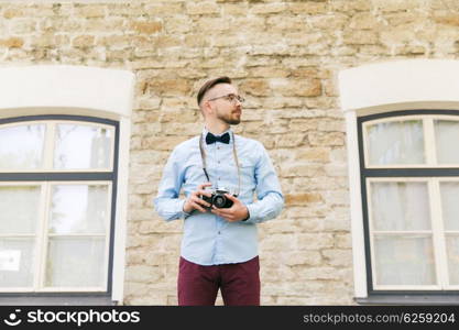 people, photography, technology, leisure and lifestyle - happy young hipster man with retro vintage film camera on city street