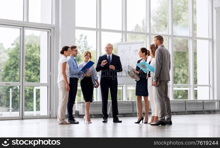 people, planning and strategy concept - business team discussing scheme on flip chart at office. business team with scheme on flip chart at office