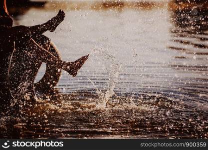 people play their feet in the water at sunset. couple splashing their feet in the water at sunset