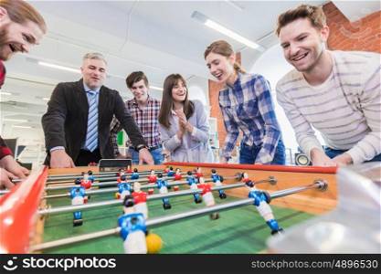 People playing table football. Employees playing table football indoor game in the office during break time