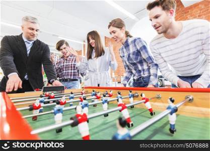People playing table soccer. Group of happy people playing table soccer together