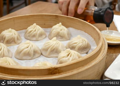 People pouring vinegar before eating soup dumpling buns in restaurant