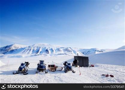 People preparing snowmobiles for an expedition through through winter conditions
