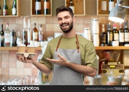 people, profession and job concept - happy smiling barman in apron holding takeaway coffee over bar background. happy smiling barman in apron with takeaway coffee