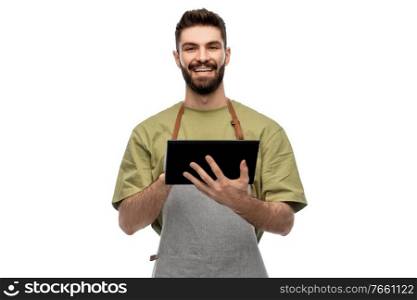 people, profession and job concept - happy smiling waiter or seller in apron with tablet pc computer over white background. smiling waiter in apron with tablet pc computer