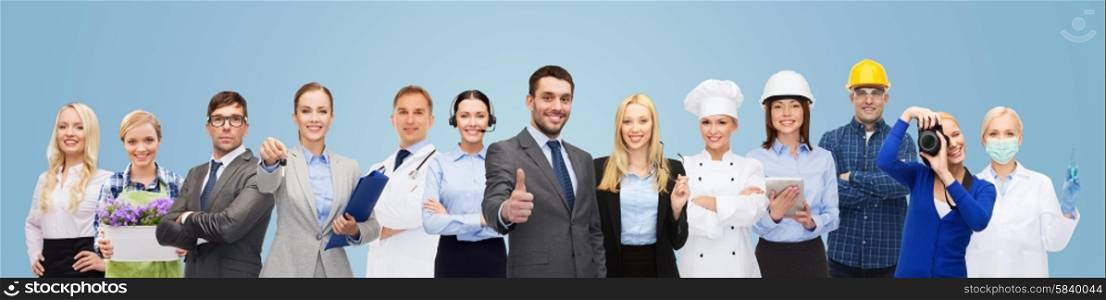 people, profession, qualification, employment and success concept - happy businessman over professional workers showing thumbs up over blue background