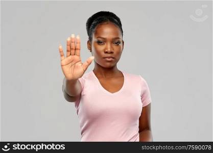 people, prohibition and rejection concept - african american young woman showing stop gesture over grey background. african american woman over grey background