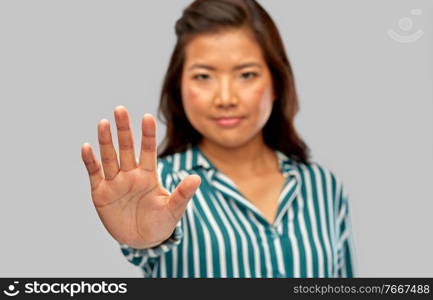 people, prohibition and rejection concept - close up of asian young woman showing stop gesture over grey background. close up of asian woman showing stop gesture