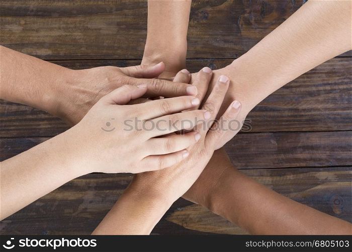 people put hand together on wooden table for use as unity teamwork concept - top view