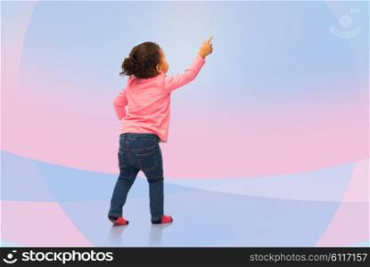 people, race, ethnicity and childhood concept - happy african american baby girl pointing finger to something from back over pink and violet background