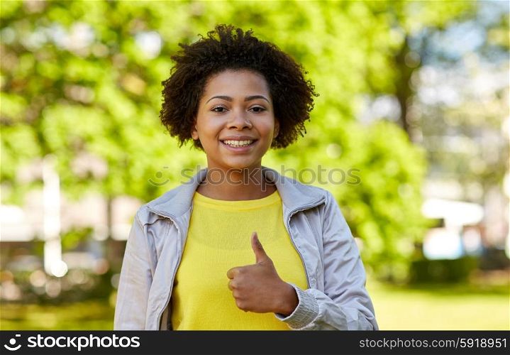 people, race, ethnicity and gesture concept - happy african american young woman showing thumbs up in summer park