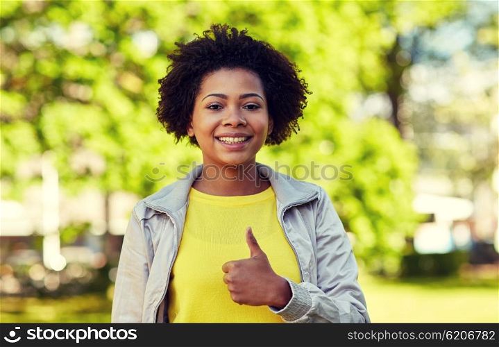 people, race, ethnicity and gesture concept - happy african american young woman showing thumbs up in summer park
