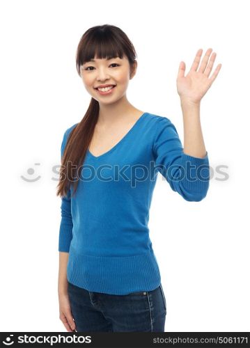 people, race, ethnicity and gesture concept - happy smiling young asian woman waving hand over white. happy smiling young woman waving hand over white