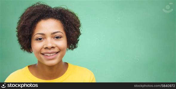 people, race, ethnicity and portrait concept - happy african american young woman face over green chalk board background