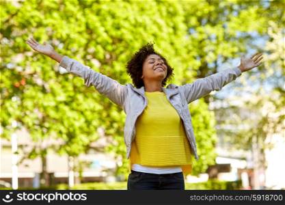 people, race, ethnicity and portrait concept - happy african american young woman with open arms in summer park