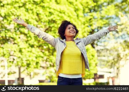 people, race, ethnicity and portrait concept - happy african american young woman with open arms in summer park