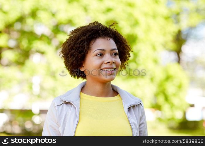 people, race, ethnicity and portrait concept - happy african american young woman in summer park