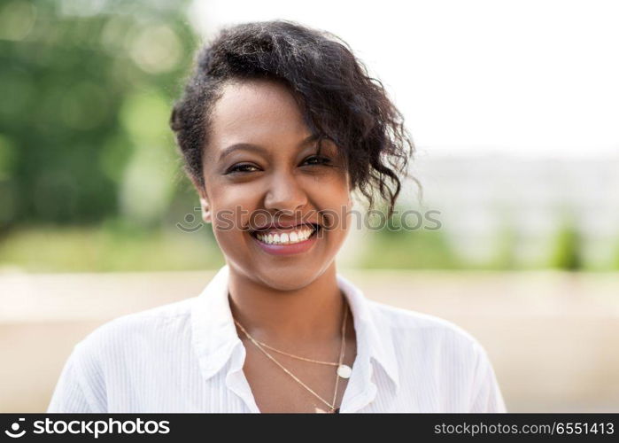 people, race, ethnicity and portrait concept - happy african american young woman outdoors in summer. happy african american young woman outdoors. happy african american young woman outdoors