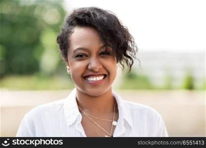people, race, ethnicity and portrait concept - happy african american young woman outdoors in summer. happy african american young woman outdoors. happy african american young woman outdoors