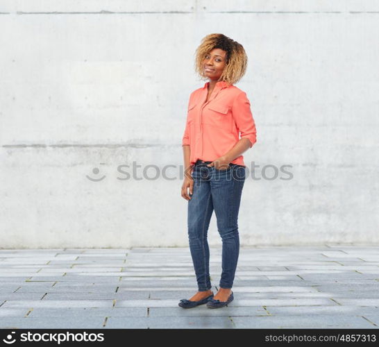 people, race, ethnicity and portrait concept - happy african american young woman over stone wall background