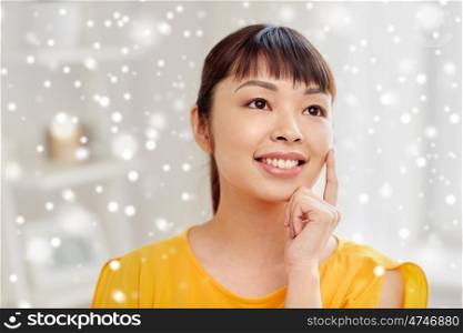 people, race, ethnicity and portrait concept - happy asian young dreaming woman or teenage girl face at home over snow