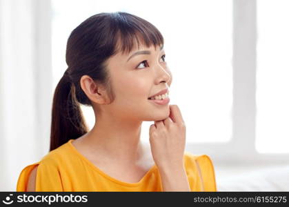 people, race, ethnicity and portrait concept - happy asian young dreaming woman or teenage girl face at home