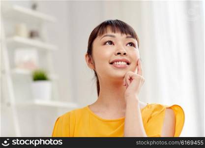 people, race, ethnicity and portrait concept - happy asian young dreaming woman or teenage girl face at home