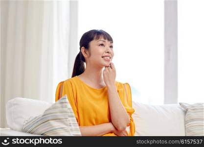 people, race, ethnicity and portrait concept - happy asian young dreaming woman at home