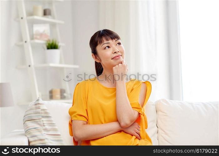 people, race, ethnicity and portrait concept - happy asian young dreaming woman at home