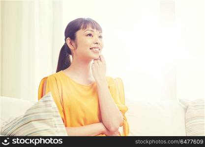 people, race, ethnicity and portrait concept - happy asian young dreaming woman at home. happy asian young dreaming woman at home. happy asian young dreaming woman at home