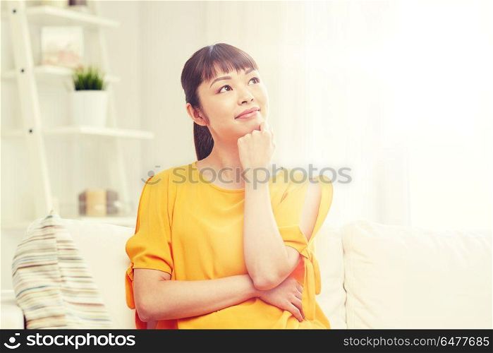people, race, ethnicity and portrait concept - happy asian young dreaming woman at home. happy asian young dreaming woman at home. happy asian young dreaming woman at home