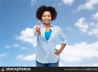 people, race, ethnicity, gesture and portrait concept - happy african american young woman showing thumbs up over blue sky and clouds background. happy african american woman showing thumbs up