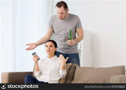 people, relationship difficulties and conflict concept - man drinking beer and woman with smartphone having argument at home. couple having argument at home