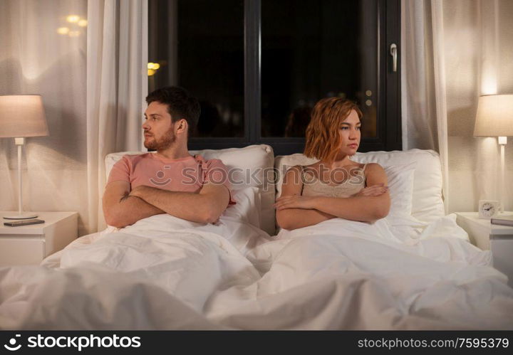 people, relationship difficulties and crisis concept - unhappy couple having conflict in bed at home. unhappy couple having conflict in bed at home