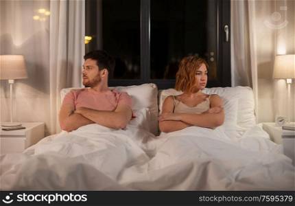people, relationship difficulties and crisis concept - unhappy couple having conflict in bed at home. unhappy couple having conflict in bed at home