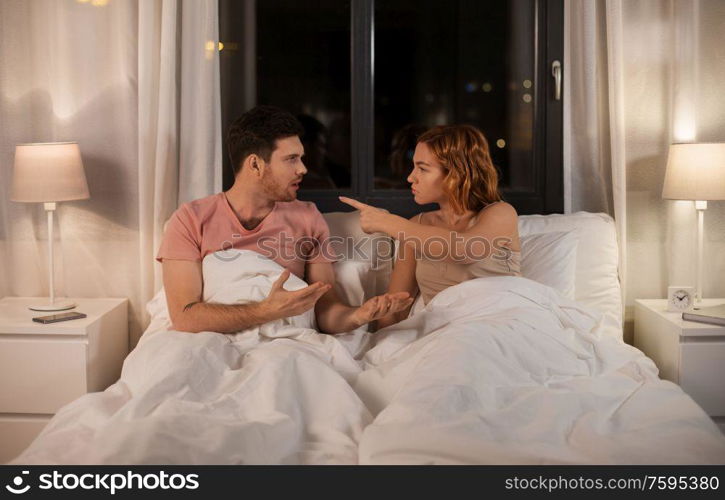 people, relationship difficulties and crisis concept - unhappy couple having conflict in bed at home. unhappy couple having conflict in bed at home