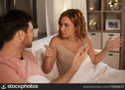people, relationship difficulties and crisis concept - unhappy couple having conflict in bed at home. unhappy couple having conflict in bed at home