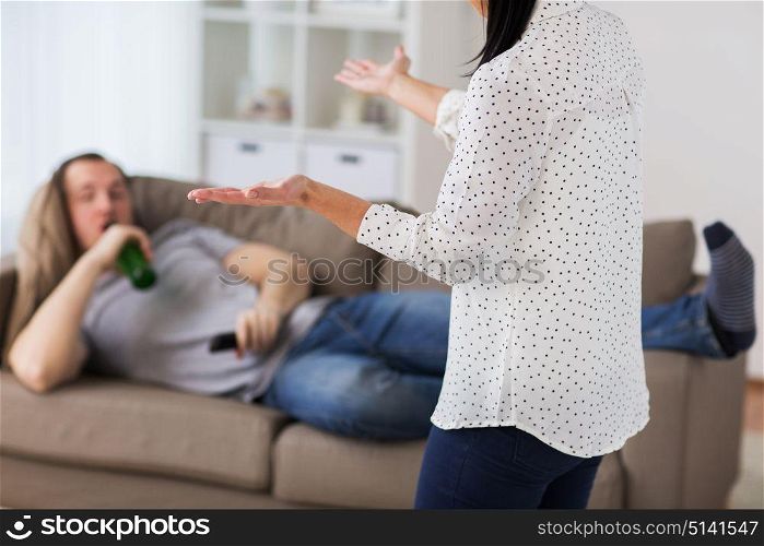 people, relationship difficulties, conflict and alcohol abuse concept - angry woman having argument with man drinking beer and watching tv at home. couple having argument at home